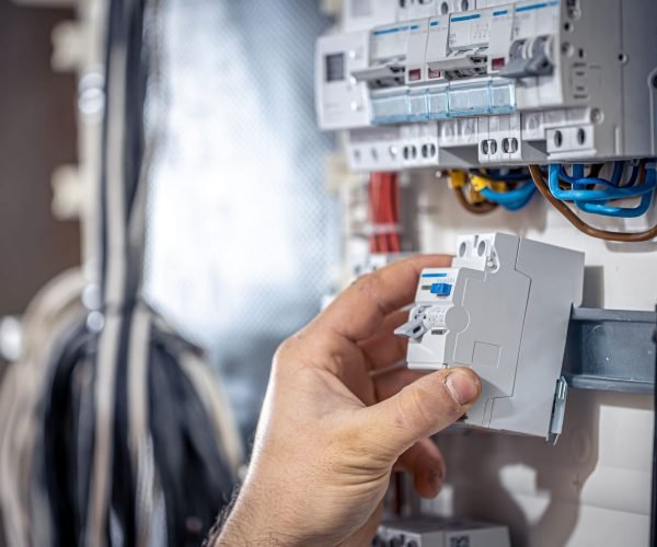 male-electrician-works-switchboard-with-electrical-connecting-cable